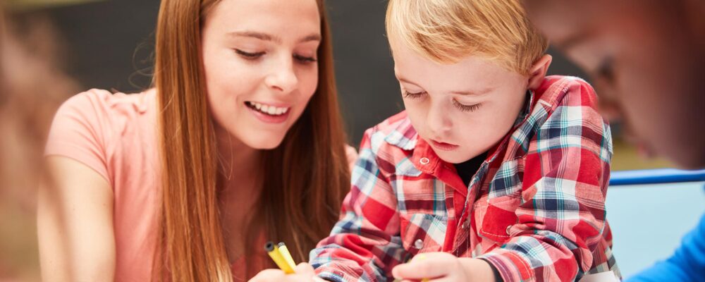 Erzieherin mal mit Kindern an einem Tisch